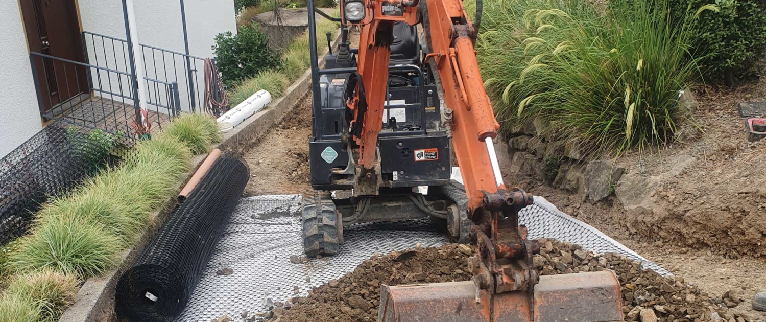 excavator working on the ground near a house