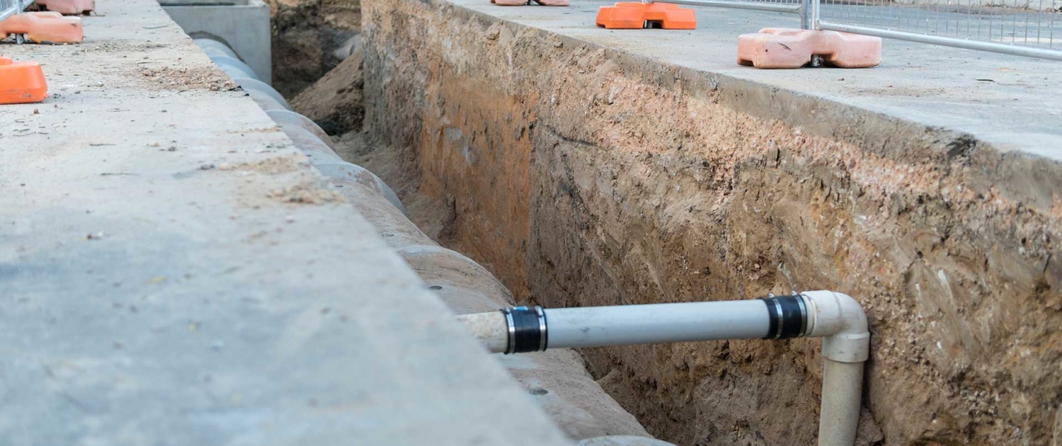 excavation site with exposed soil, and showing drainage pipes